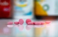 Pink tablets pills on blurred background of drug box and drug bottle. Vitamins and supplements tablets. Pharmacy drugstore. Royalty Free Stock Photo
