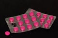 Pink tablets (pills) in a blister on black background Royalty Free Stock Photo