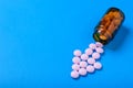 Pink tablets are poured from a glass bubble in the form of an arrow on a blue background Royalty Free Stock Photo