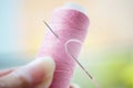 Pink thread spool with needle in a female hand, macro photo Royalty Free Stock Photo