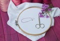 Pink thread and white fabric in the wooden embroidery frame for