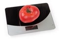 Pink tomato on the digital kitchen scale on white background Royalty Free Stock Photo