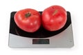 Pink tomatoes on the digital kitchen scale on white background Royalty Free Stock Photo