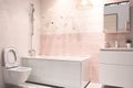 Pink tones modern bathroom interior with hanging toilet, sink, bath, faucet, mirror, shower, furniture and accessories Royalty Free Stock Photo