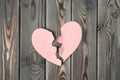 Pink torn paper heart halves laying together on dark wooden table. Broken heart, breaking up. Saint valentines day love