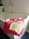 Pink towel on bathtub with bath glove