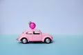 Pink toy car with a Christmas ball on the roof. Miniature automobile with a Christmas decoration on a blue background Royalty Free Stock Photo