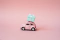 Pink toy retro model car delivering gift box for Valentine`s day on pink background. Volkswagen Beetle on pink background. Royalty Free Stock Photo