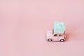 Pink toy retro model car delivering gift box for Valentine`s day on pink background. Volkswagen Beetle on pink background. Royalty Free Stock Photo