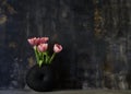 Pink tulip bouquet in black vase on table on dark background. Copy space for text Royalty Free Stock Photo