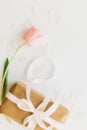 Pink tulip flat lay and gift box with ribbon on white background, space for text. Stylish vertical image. Happy womens day.