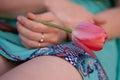 Pink tulip in the left woman hand. Girl in green dress holding a flower. Royalty Free Stock Photo