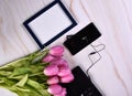 Pink tulips, black laptop, phone, headphone and photo frame on a light background Royalty Free Stock Photo