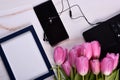 Pink tulips, black laptop, phone, headphone and photo frame on a light background Royalty Free Stock Photo