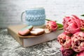 Pink tulips blurred foreground, open book and a mug of freshly brewed coffee or tea. Spring set. Royalty Free Stock Photo