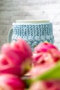 Pink tulips blurred foreground, open book and a mug of freshly brewed coffee or tea. Spring set. Royalty Free Stock Photo