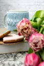 Pink tulips blurred foreground, open book and a mug of freshly brewed coffee or tea. Spring set. Royalty Free Stock Photo