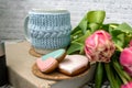 Pink tulips blurred foreground, open book and a mug of freshly brewed coffee or tea. Spring set. Royalty Free Stock Photo