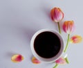 Pink tulips, coffee cup and notebook over white wbackground in a flat lay composition