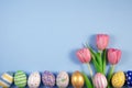 Pink tulips flowers and colourful eggs on blue background. Card for Happy Easter. Waiting for spring Royalty Free Stock Photo