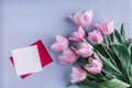 Pink tulips flowers and sheet of paper over light blue background. Greeting card or wedding invitation. Royalty Free Stock Photo