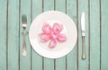 Pink tulips heads over plate with silverware on shabby chic wood