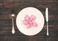 Pink tulips heads over plate on wooden table. Top view with copy