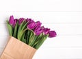 Pink tulips in a paper bag on the white wooden table Royalty Free Stock Photo