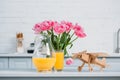 Pink tulips in vase, orange juice and wooden airplane on table