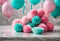 Pink and turquoise pastel colored tissue pompoms and balloons on marble table