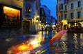 pink umbrella on wet pavement at rainy medieval evening street people walking in the rain light blurred reflektion rain fall old