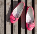 Pink used shoes on a latticed wooden floor