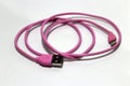Pink used USB plug with cable on the white background.