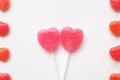 Pink Valentine`s day heart shape lollipop small red candy in cute pattern on empty white paper background. love concept. top view. Royalty Free Stock Photo