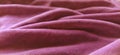 Pink velvet is folded by beautiful waves. Retro style. Soft pleasant fabric for sewing clothes, items for the interior, for