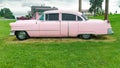 pink vintage Cadillac stands on the lawn near a roadside cafe