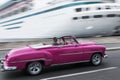 Pink vintage convertible car passing a blurred cruise ship in Havana Cuba Royalty Free Stock Photo