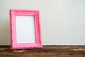 Pink vintage photo frame on old wooden table over white wall background Royalty Free Stock Photo