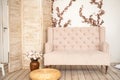 Pink vintage sofa and screen in rustic style. Interior of a bright Scandinavian living room with flowers on the wall Royalty Free Stock Photo