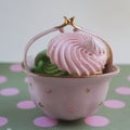 Pink vintage vase with pink meringue on a green background with pinky dots.