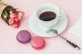 Pink and vioet macarons, macaroons, bouquet of spring flowers and cup of coffee, spoon, top view. Romantic morning, gift