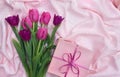 Pink, violet tulips on background with pink gift box on pink linen cloth with space for text. Holiday spring composition Royalty Free Stock Photo