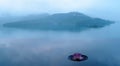 A pink water lily blooming on an infinity pool with foggy mountains in background under moody cloudy sky in a peaceful Zen atmosph Royalty Free Stock Photo