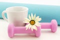 Pink weights, turquoise yoga mat, and white mug still life