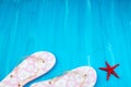 Pink with white flowers flip flop sandals beach shoes on blue wooden floor. Top view and copy space. Royalty Free Stock Photo