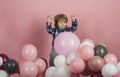 Pink, white and gray balloons for celebration. Funny kid play on his own on pink background. Cute boy wearing blue shirt Royalty Free Stock Photo