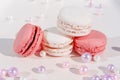 Pink and white macarons on light wooden background with beautiful pearls decoration. French Pastel Macaroons. Blurred focus