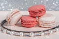 Pink and white macarons on light wooden background with beautiful pearls decoration. French Pastel Macaroons. Blurred focus