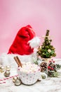 Pink white mug with marshmallows, Christmas tree, ornaments and Santa Claus hat on a marble and pink background Royalty Free Stock Photo