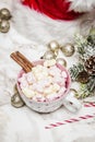 Pink white mug with marshmallows, Christmas tree, ornaments and Santa Claus hat on a marble and pink background Royalty Free Stock Photo